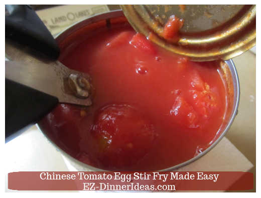 Using scissors roughly cut up the canned tomatoes Using scissors roughly cut up the canned tomatoes